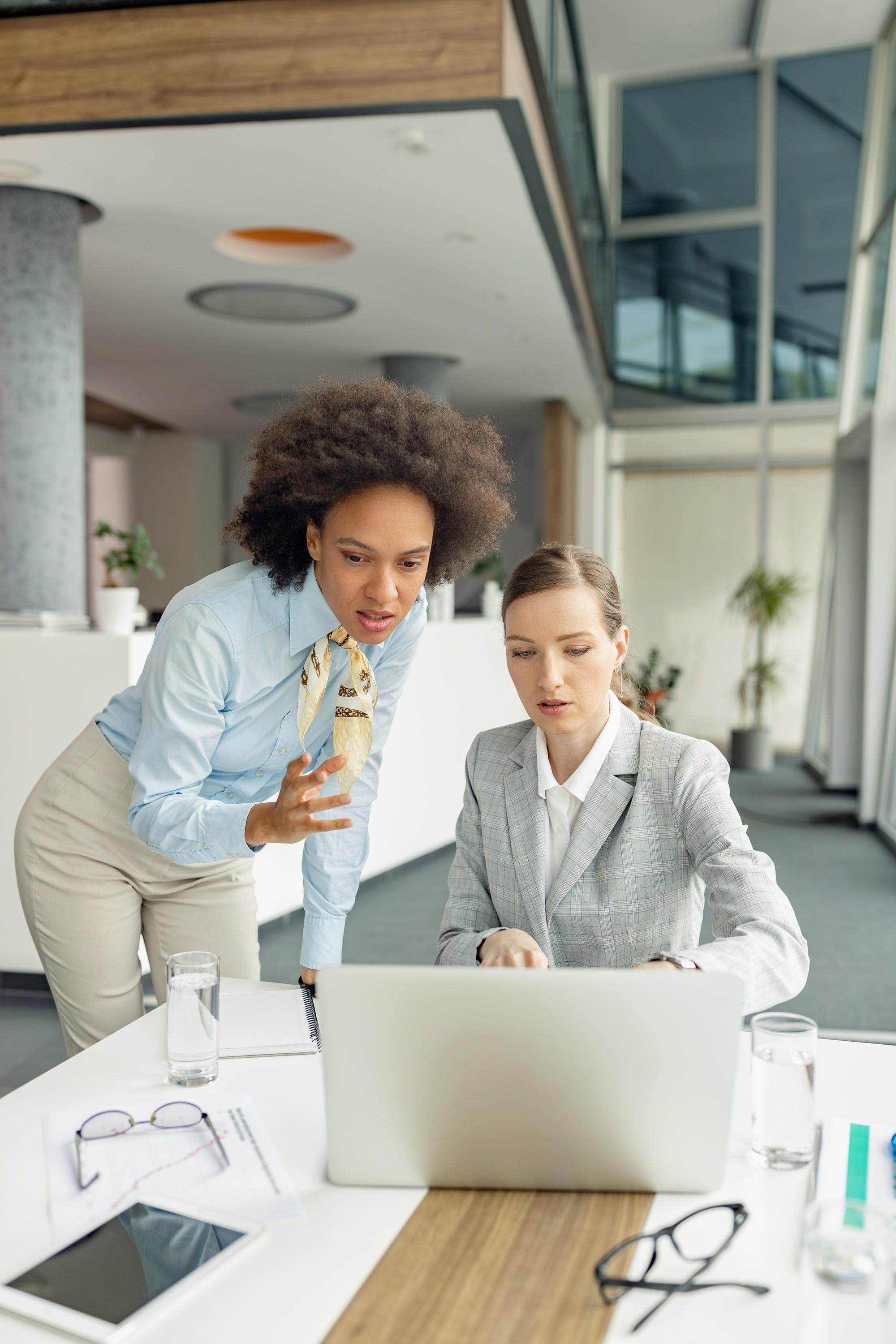 Two businesswomen reviewing information on a laptop together in a modern office