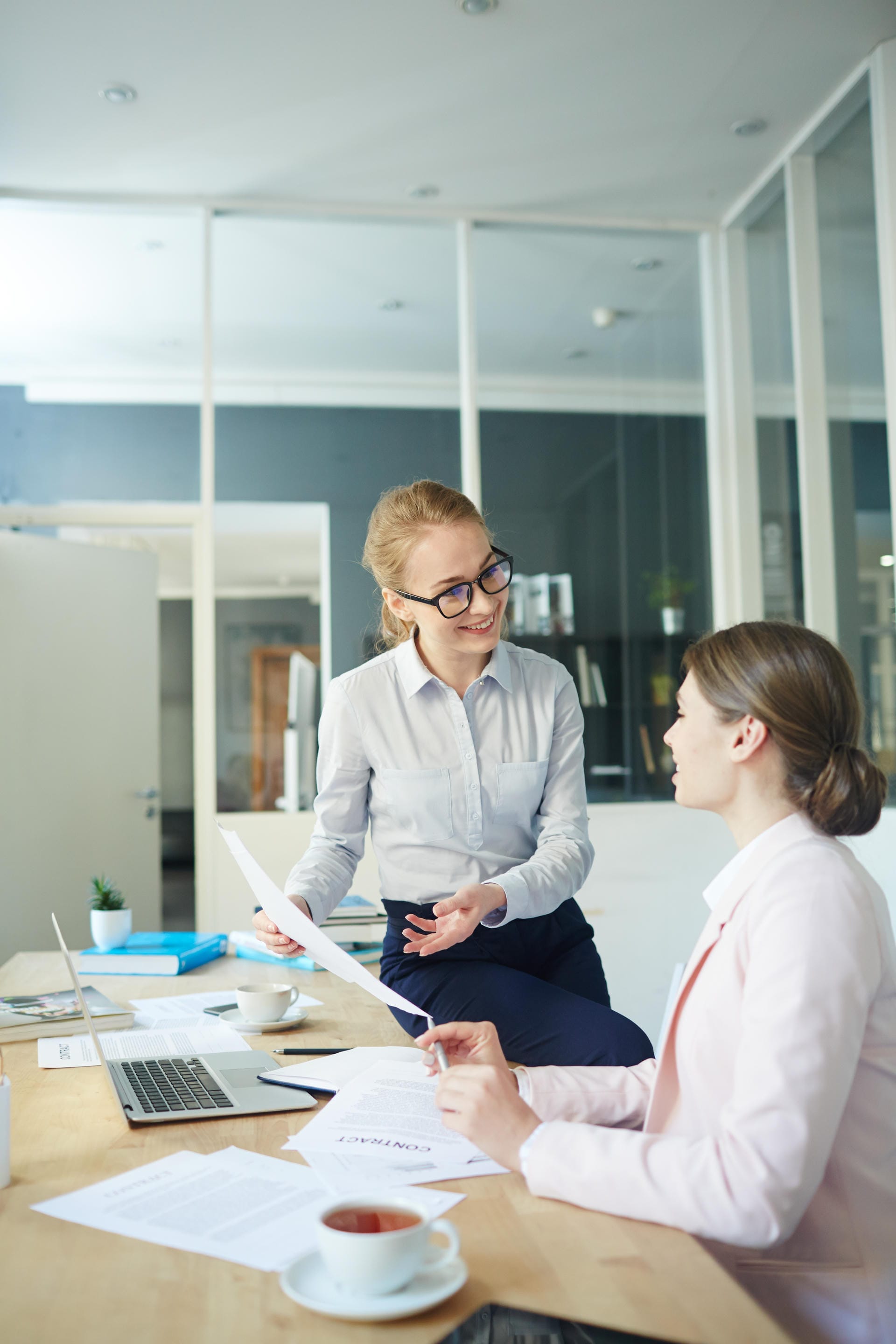 Businesswoman explaining a contract to a seated colleague in a modern office